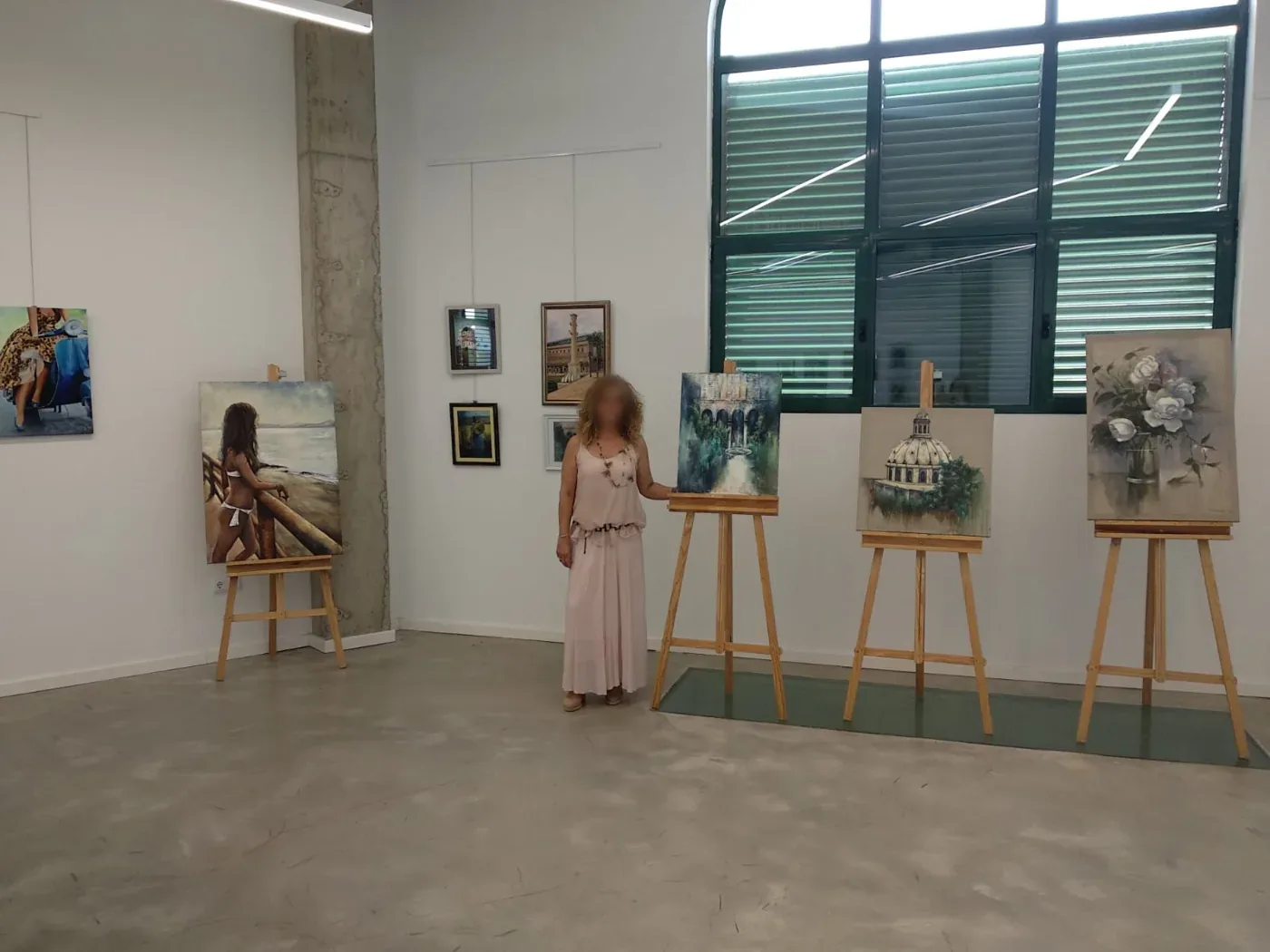 Visitantes recorriendo una exposición de obras en caballetes
